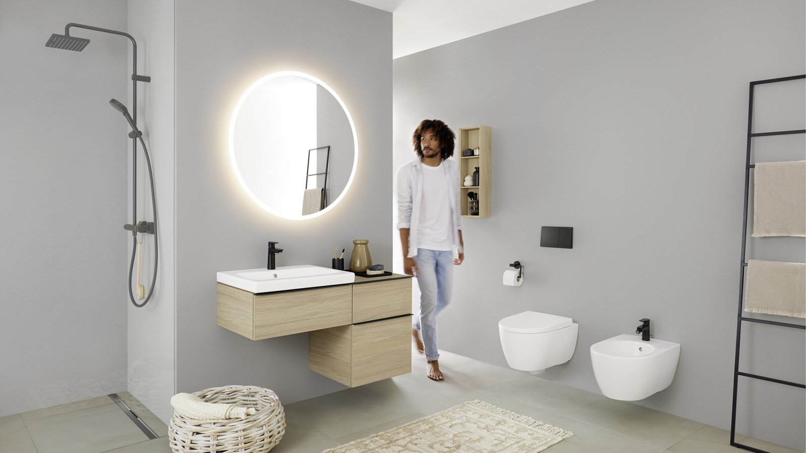 Mees astub vannituppa, kus on kraanikauss, WC, bidee ja vannitoamööbel Geberit iCon vannitoaseeriast Mees astub vannituppa, kus on kraanikauss, WC, bidee ja vannitoamööbel Geberit iCon vannitoaseeriast