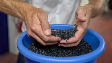 Käed, mis hoiavad musti plast-pelleteid (© Ben Huggler)