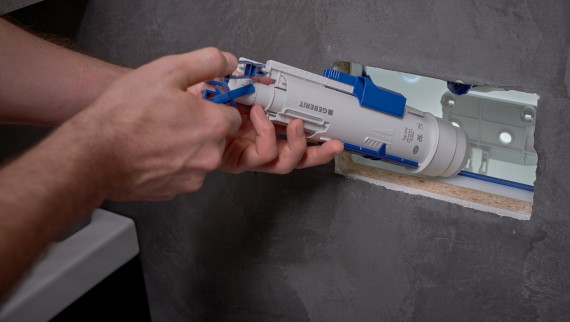 Mees paigaldab ettevõtte Geberit loputusklappi varjatud loputuskasti (© Ben Huggler)