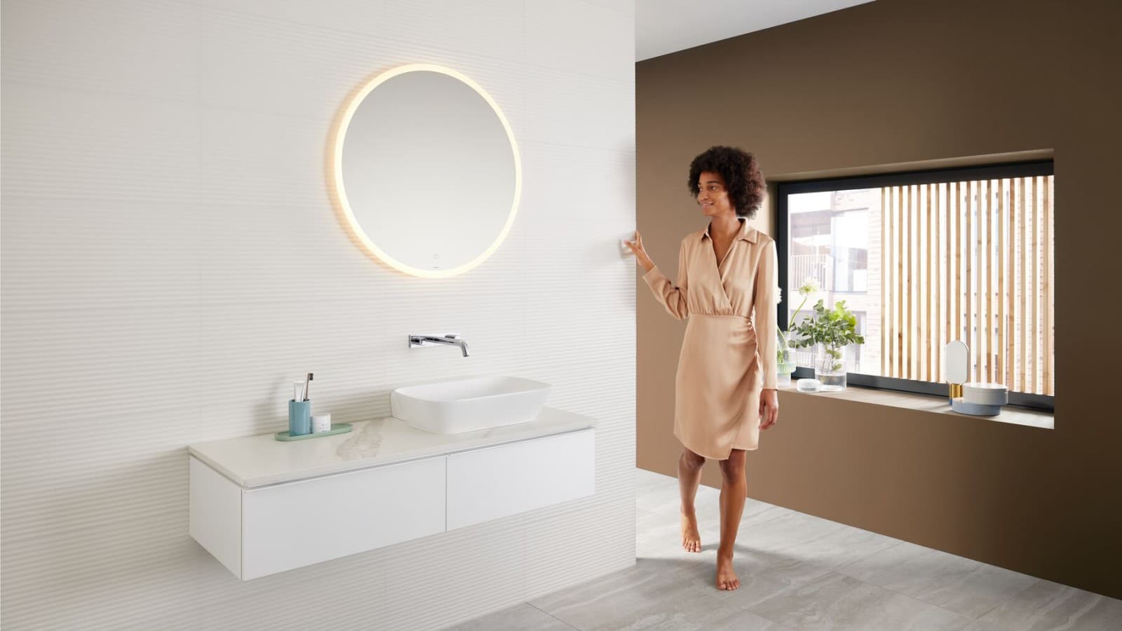 Woman in a modern bathroom featuring a brown colour scheme – the latest bathroom colour trend – and a Mix & Match washbasin area combination Woman in a modern bathroom featuring a brown colour scheme – the latest bathroom colour trend – and a Mix & Match washbasin area combination